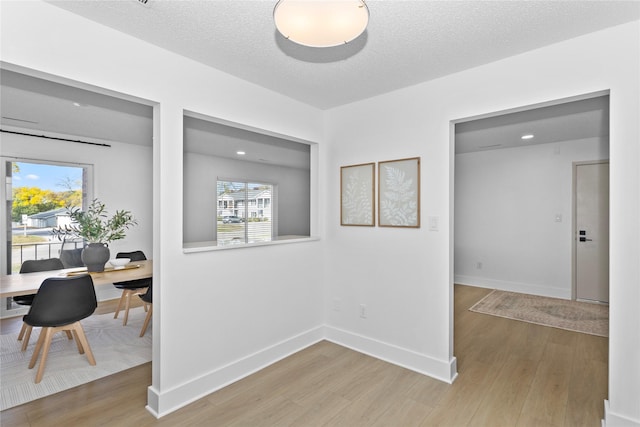 interior space with light wood-type flooring, baseboards, and a textured ceiling