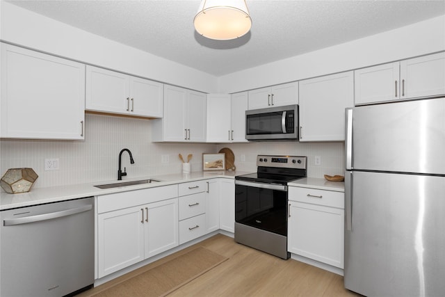 kitchen featuring appliances with stainless steel finishes, light countertops, white cabinetry, and a sink