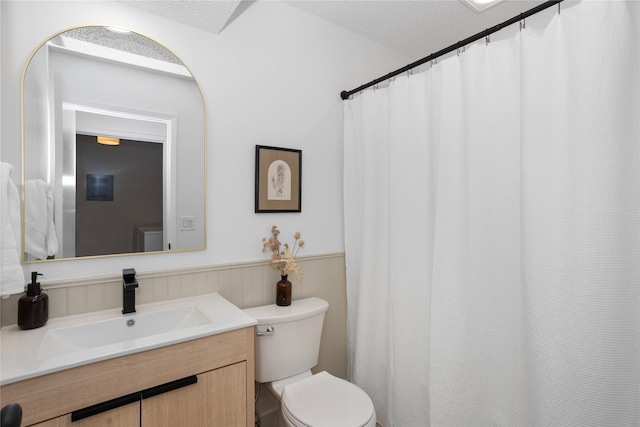 bathroom with toilet, a wainscoted wall, and vanity