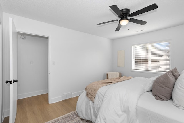 bedroom featuring visible vents, light wood-style floors, ceiling fan, a textured ceiling, and baseboards