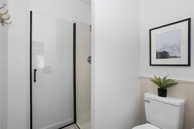 bathroom with wainscoting, a shower stall, and toilet