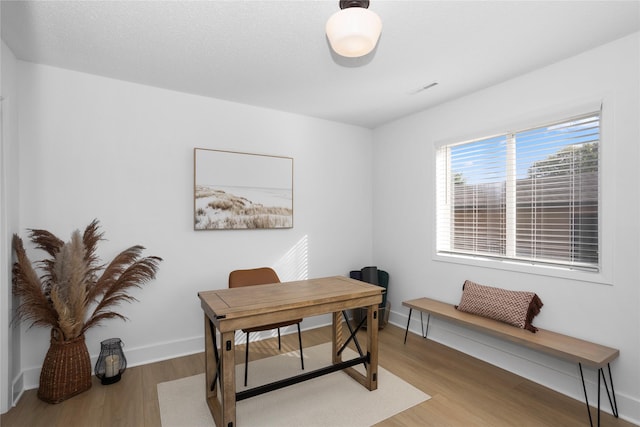 home office featuring light wood-style flooring, visible vents, and baseboards