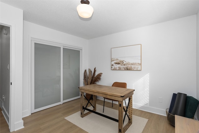 office with a textured ceiling, baseboards, and wood finished floors