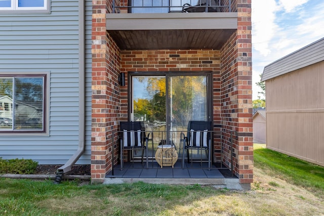 entrance to property with brick siding and a balcony