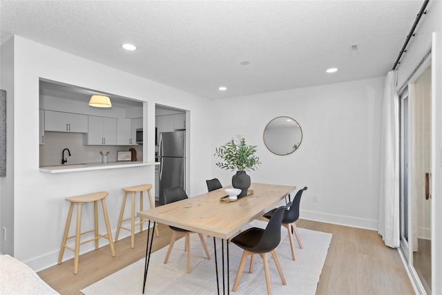 dining space with recessed lighting, baseboards, light wood-style flooring, and a textured ceiling