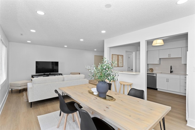 dining area featuring light wood-type flooring, a textured ceiling, and recessed lighting