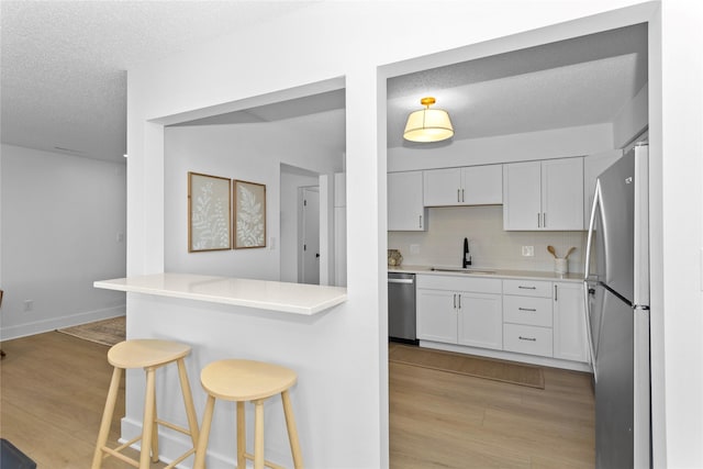 kitchen featuring appliances with stainless steel finishes, light wood-type flooring, a sink, and a breakfast bar