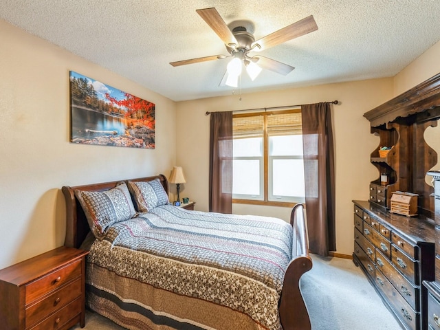 bedroom with a ceiling fan, light carpet, and a textured ceiling