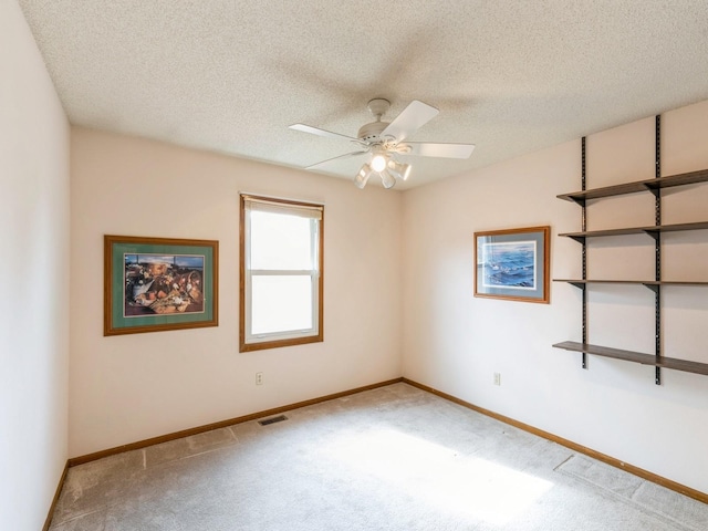 carpeted spare room with ceiling fan, a textured ceiling, and baseboards