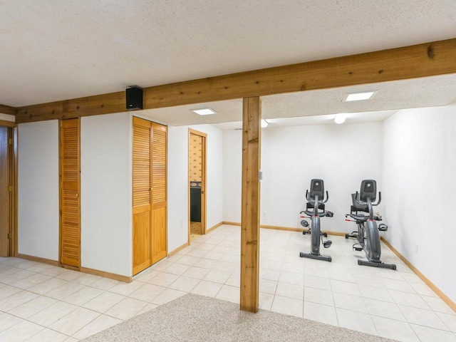 exercise area with light tile patterned floors, baseboards, a textured ceiling, and light colored carpet