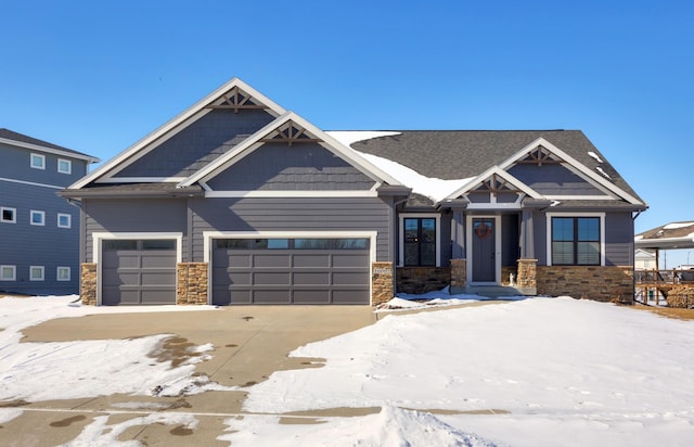 craftsman house with stone siding, an attached garage, and driveway