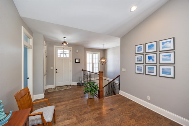 entrance foyer featuring lofted ceiling, baseboards, a chandelier, and wood finished floors