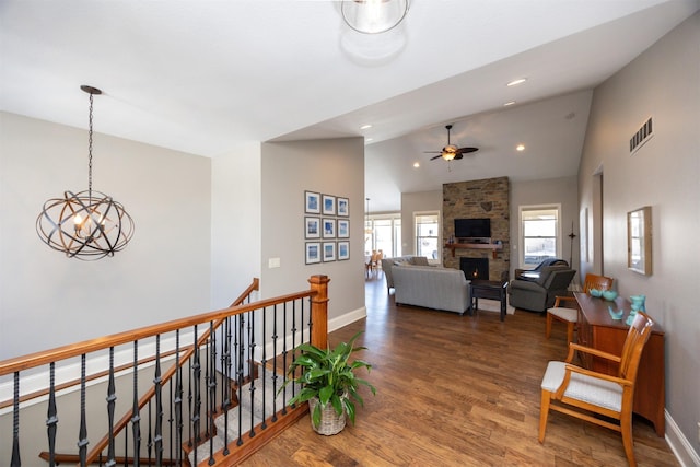 hallway with baseboards, visible vents, wood finished floors, an upstairs landing, and high vaulted ceiling