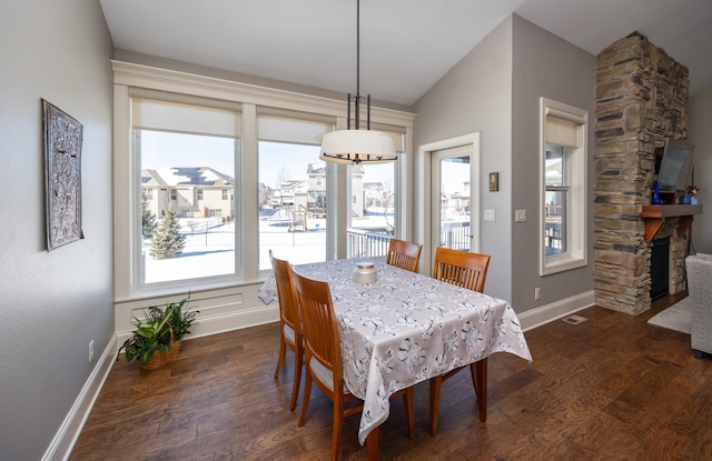 dining area with dark wood-style flooring, visible vents, a fireplace, and baseboards