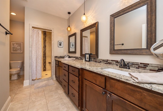 full bathroom featuring double vanity, a stall shower, a sink, and toilet