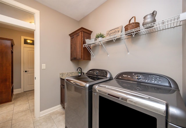 laundry area featuring light tile patterned floors, washing machine and clothes dryer, cabinet space, and baseboards