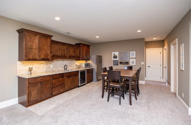 kitchen featuring wine cooler, light carpet, a sink, appliances with stainless steel finishes, and decorative backsplash