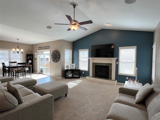 living room with a textured ceiling, light carpet, ceiling fan with notable chandelier, a fireplace, and vaulted ceiling