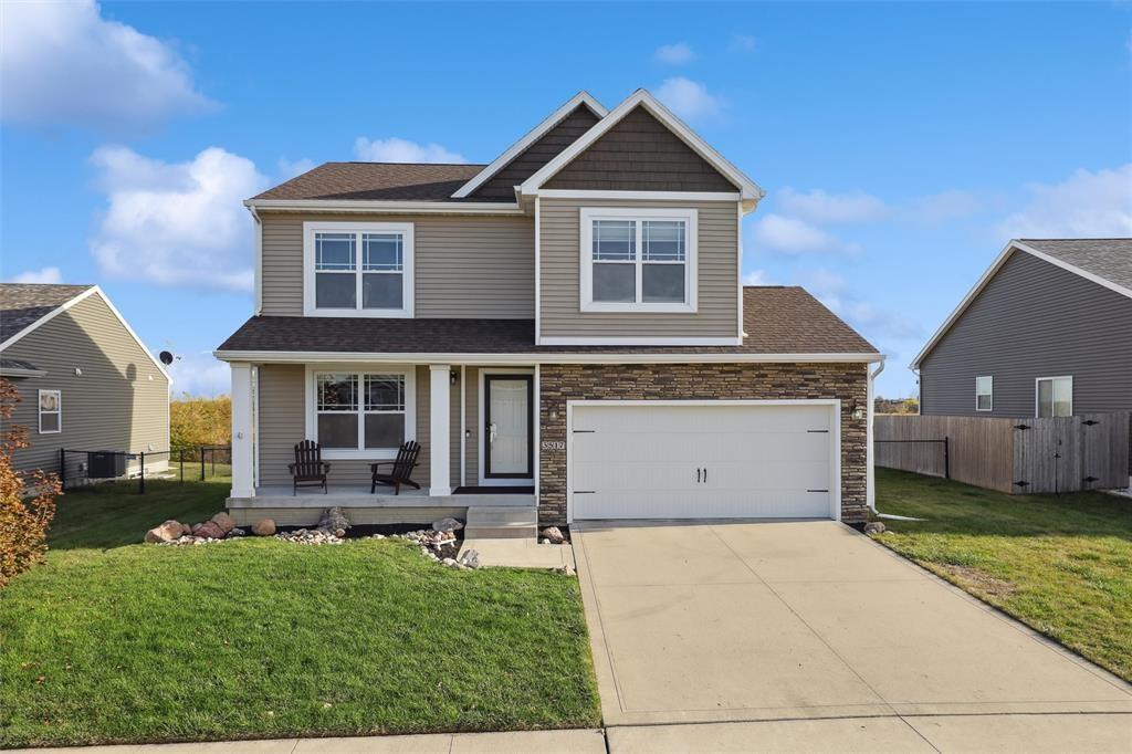 craftsman-style home featuring covered porch, driveway, a front yard, and fence