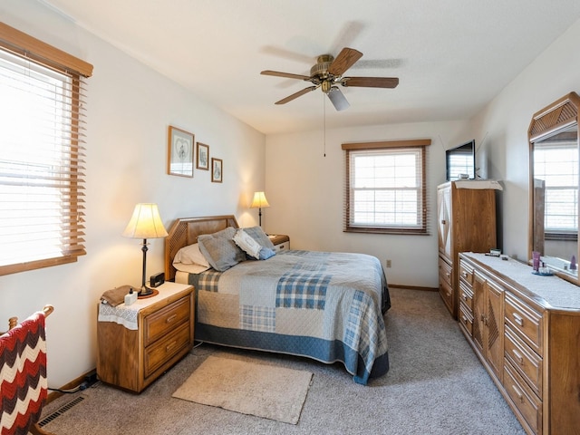 bedroom with ceiling fan, visible vents, baseboards, and light colored carpet