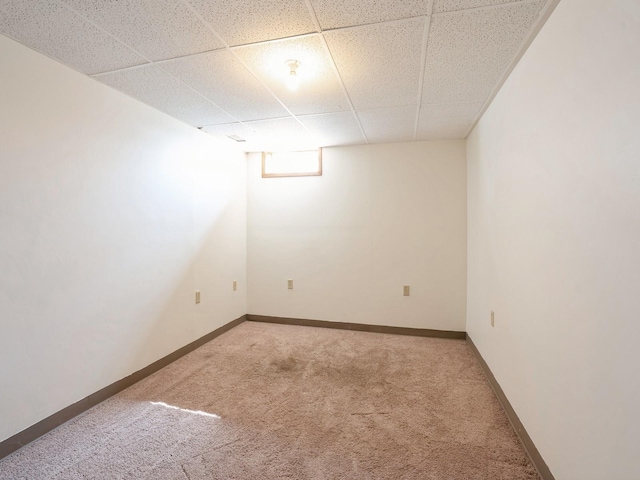 below grade area with carpet, a drop ceiling, and baseboards