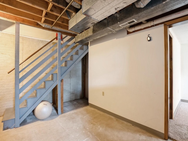 unfinished basement featuring visible vents, baseboards, and stairs