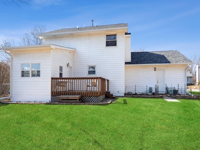 back of property featuring a shingled roof, a lawn, a wooden deck, and fence