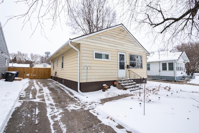 bungalow-style home featuring entry steps and fence