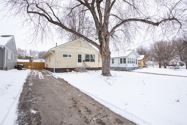 snow covered back of property with entry steps and fence