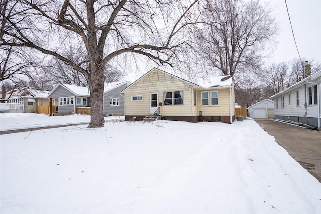 snow covered rear of property featuring entry steps, a detached garage, and an outdoor structure