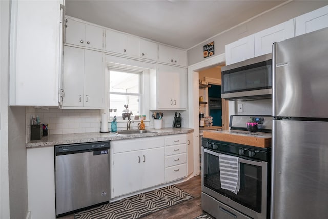 kitchen with stainless steel appliances, a sink, white cabinetry, light countertops, and decorative backsplash