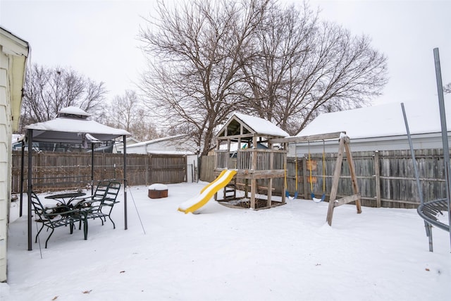 snow covered playground with a playground and a fenced backyard