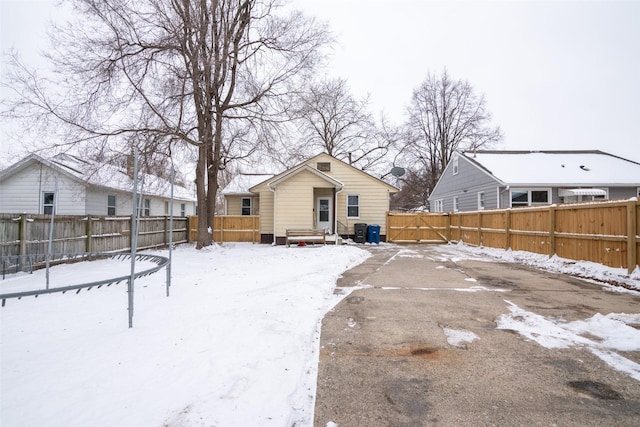 snow covered back of property with a fenced backyard