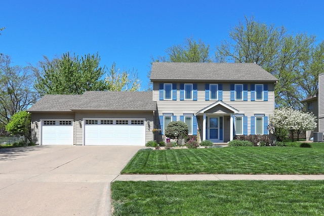 colonial home featuring central AC unit, an attached garage, driveway, and a front lawn