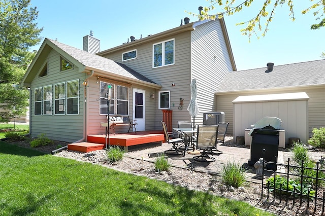 back of property with roof with shingles, a lawn, a deck, a patio area, and an attached garage