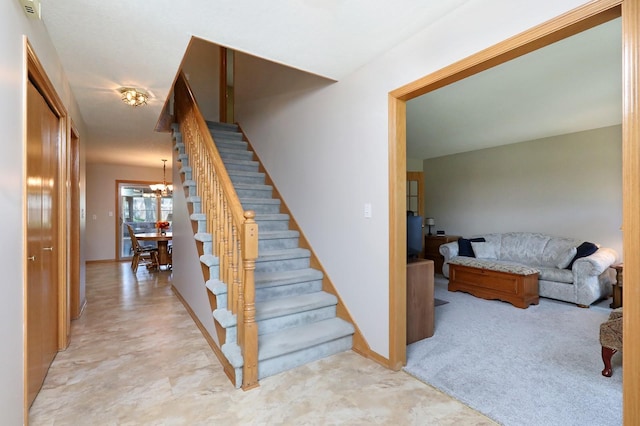 stairway with carpet floors and a chandelier