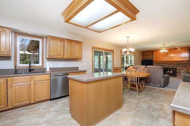 kitchen with a sink, stainless steel dishwasher, a stone fireplace, and a wealth of natural light