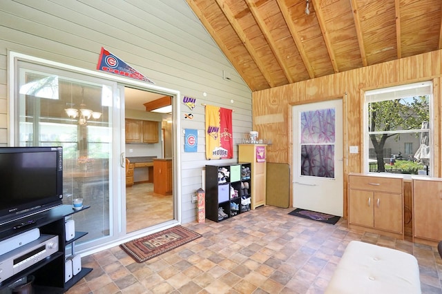 interior space featuring an inviting chandelier, high vaulted ceiling, wood walls, stone finish flooring, and wooden ceiling