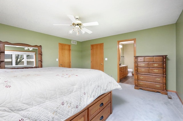 bedroom with visible vents, baseboards, ensuite bathroom, ceiling fan, and light colored carpet