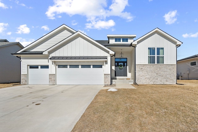 view of front of house with an attached garage, stone siding, driveway, and board and batten siding