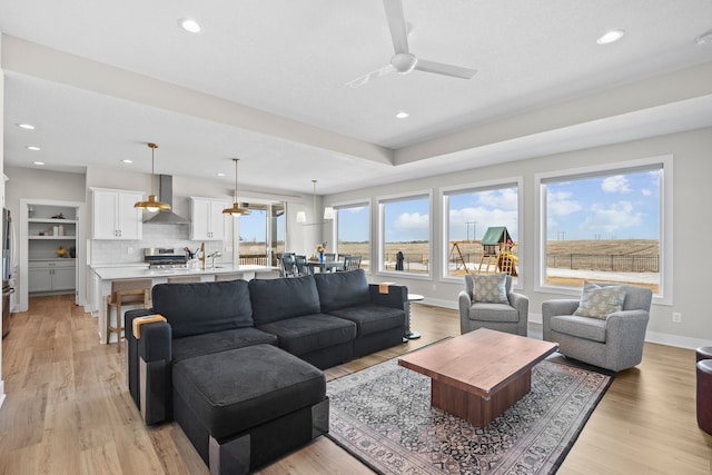 living area featuring light wood-style flooring, baseboards, and recessed lighting