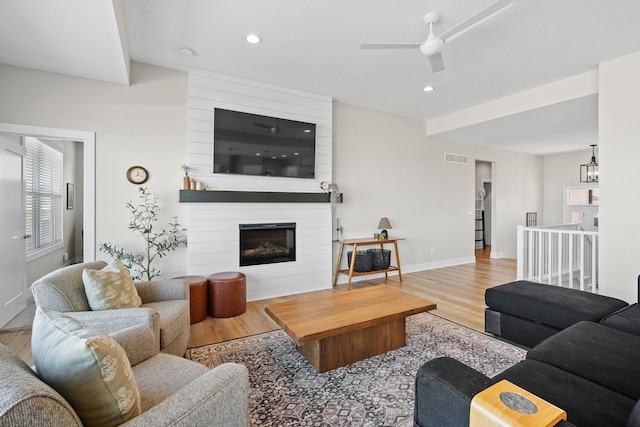 living room with a large fireplace, baseboards, wood finished floors, and recessed lighting