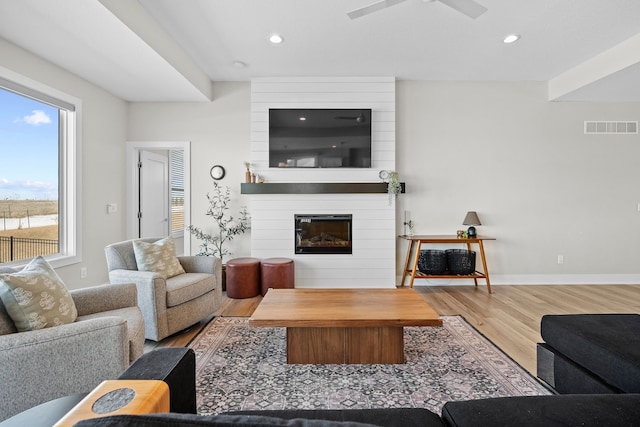 living room with recessed lighting, a fireplace, wood finished floors, visible vents, and baseboards