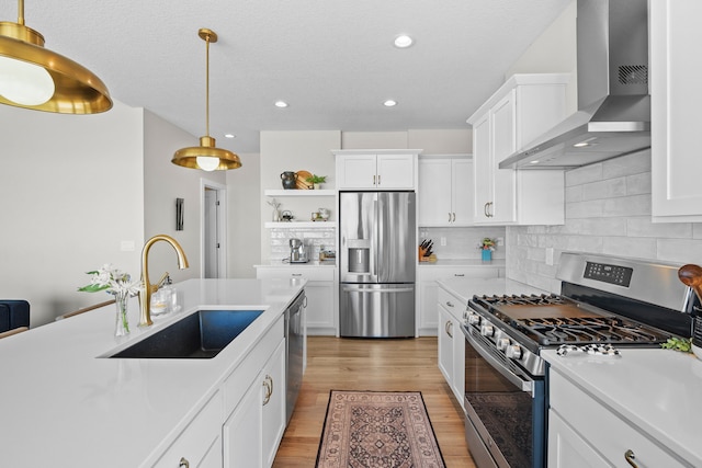 kitchen with stainless steel appliances, a sink, light countertops, wall chimney range hood, and open shelves