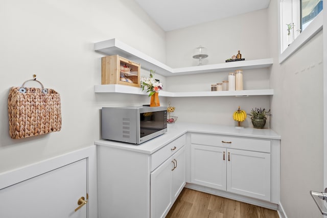 bar featuring light wood-type flooring and stainless steel microwave