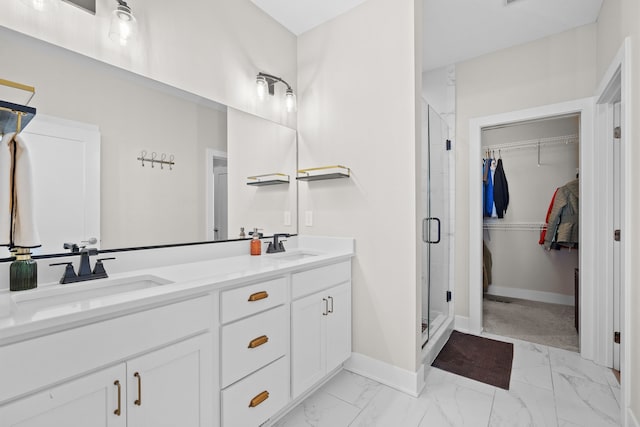 full bath featuring marble finish floor, a sink, a spacious closet, and a shower stall