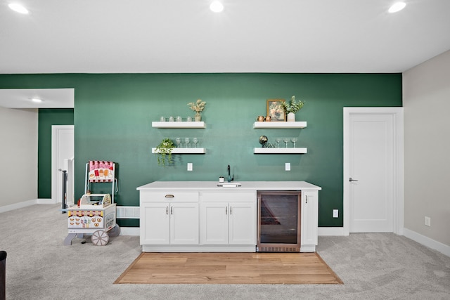 bar featuring light carpet, beverage cooler, baseboards, wet bar, and a sink