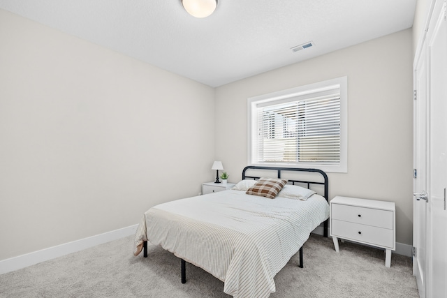 bedroom with baseboards, visible vents, and light colored carpet