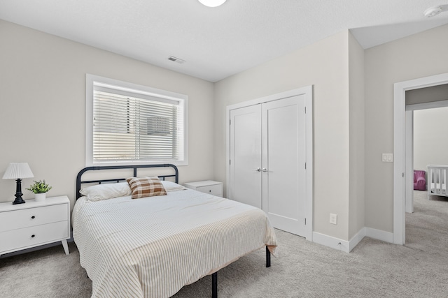 bedroom with light carpet, visible vents, baseboards, and a closet