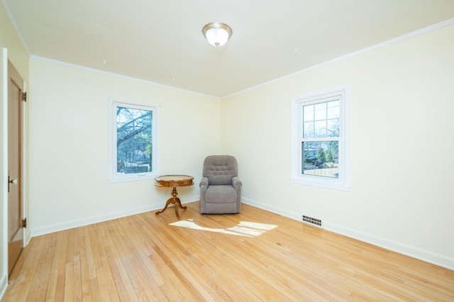 sitting room with a healthy amount of sunlight, wood-type flooring, visible vents, and baseboards